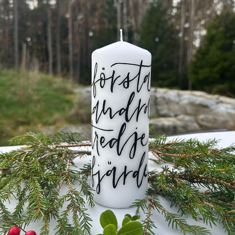 En vitt blockljus handmålat med första andra tredje fjärde. Handmålat adventsljus