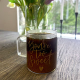 Kaffemugg i glas, graverad med orden You're too sweet och ett hjärta. Graveringen är förgylld. 