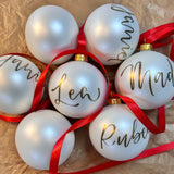 Vita julgranskulor med namn, med röda snören