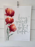 Målning och kalligrafi med blommor och texten Loving yourself is the greatest revolution. Målade röda blommor och grön text i kalligrafi