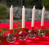 fyra adventsjuksstakar av kristallklot med handgraverade och handmålade ord; första, andra, tredje, fjärde med granris i bakgrunden