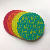 Fyra underlägg i somriga färger, som det står Skål på i kalligrafi, på vit bakgrund. 